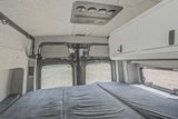 This RV rental interior features a cozy bed, overhead AC, and storage cabinets, ideal for comfortable camper van adventures.