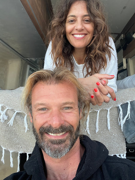 A happy couple smiles in a selfie from their cozy RV rental. Inside a camper van, ready for their road trip adventure.