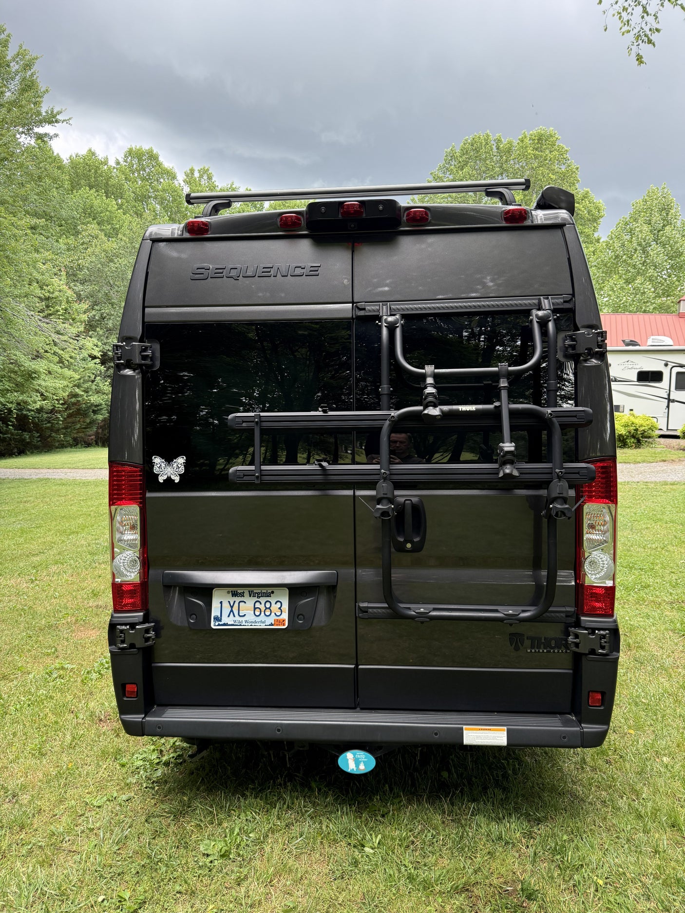 Rear view of a gray Thor Motor Coach Sequence camper van with a WV plate & Thule bike rack, perfect for your rv rental.