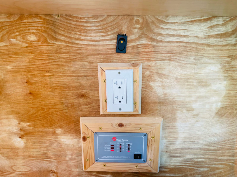 RV rental interior: a power management panel, AC outlet, and switch are neatly mounted on a wooden wall. — photo 17
