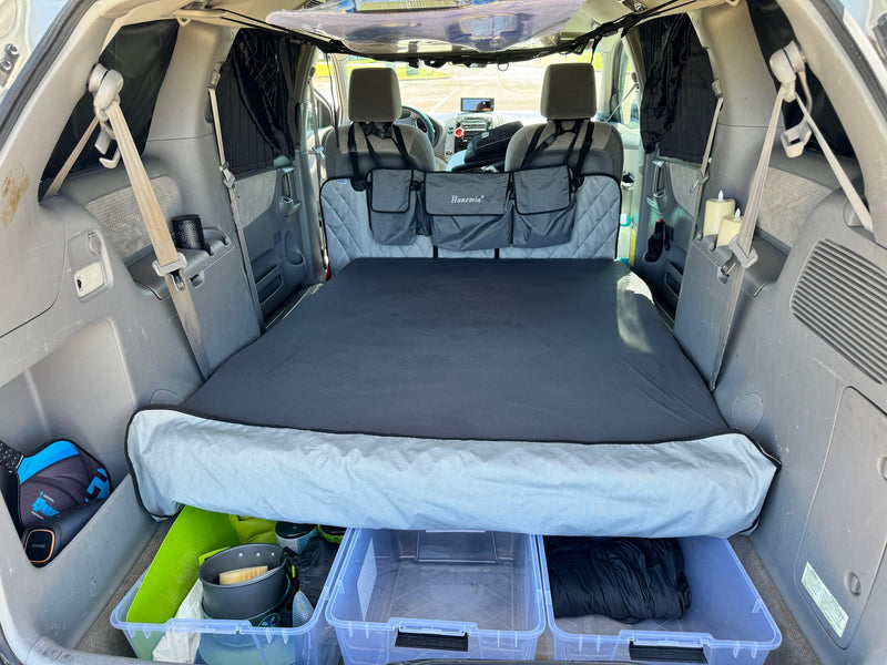 Car interior converted into a sleeping space, perfect for an RV rental alternative. Camping setup with bed, storage, and privacy. — photo 8