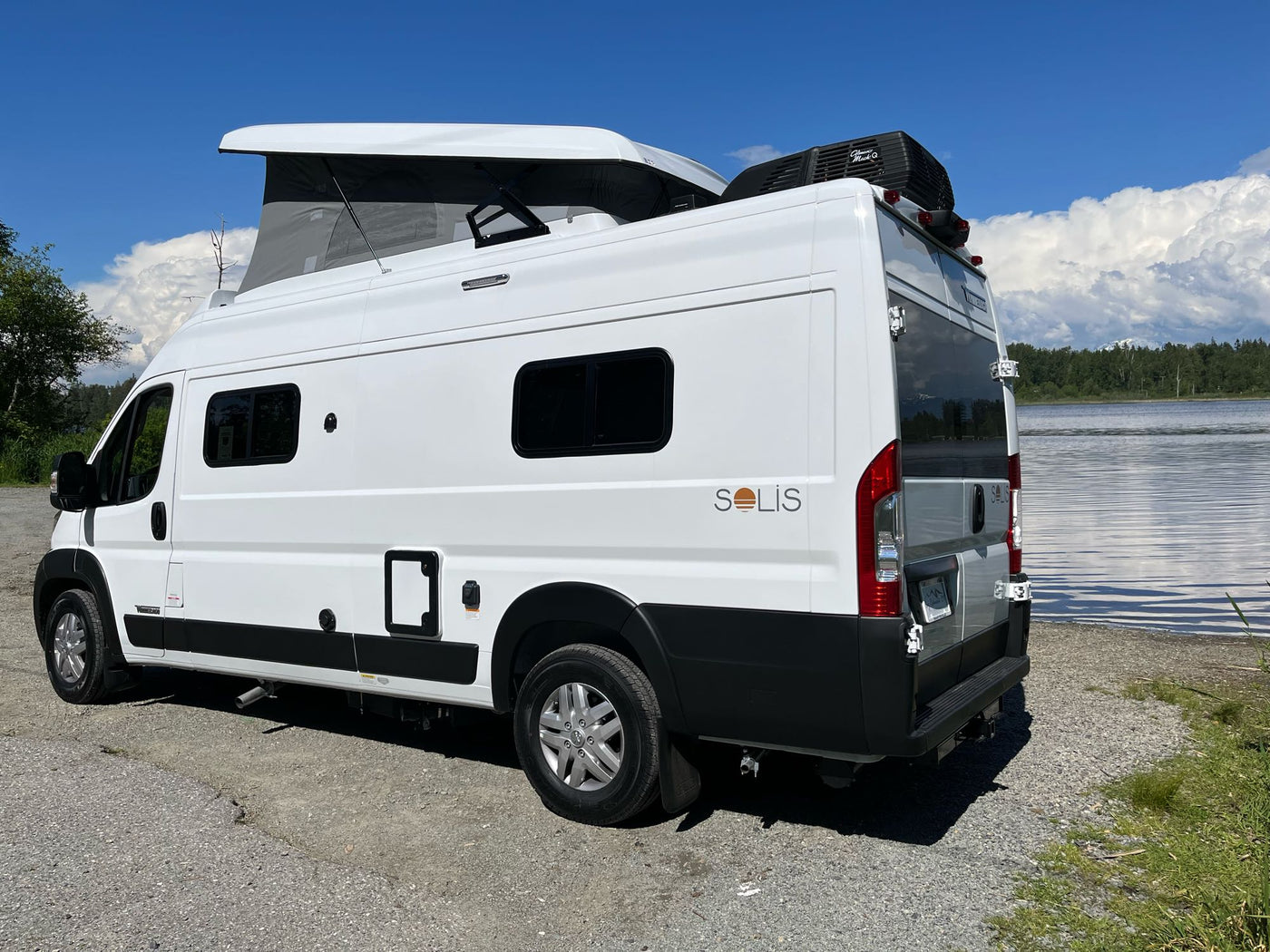  parked by a scenic lake.|White Solis pop-top RV rental parked by a clear lake under a blue sky — photo 2
