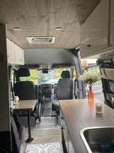 Spacious RV rental interior featuring a modern wood ceiling, kitchenette, seating area, and cozy accents. Perfect for mobile adventures.