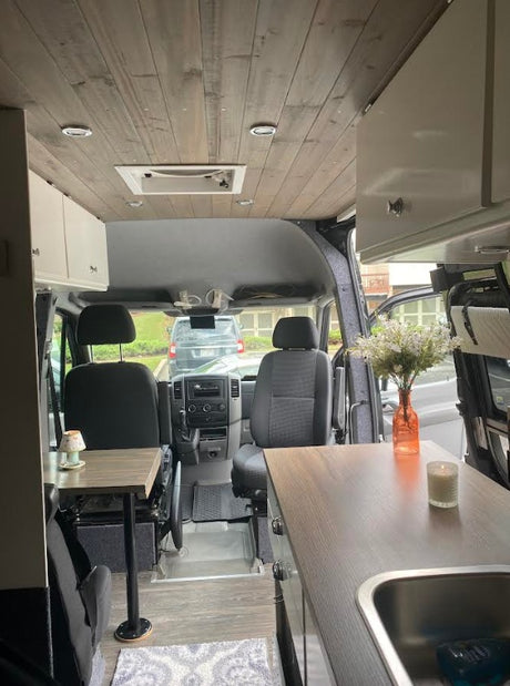 Spacious RV rental interior featuring a modern wood ceiling, kitchenette, seating area, and cozy accents. Perfect for mobile adventures.