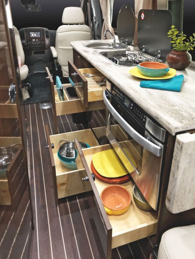 See a compact RV rental kitchen featuring a sink, stovetop, oven, and smart pull-out storage for cookware and dishes. — photo 7