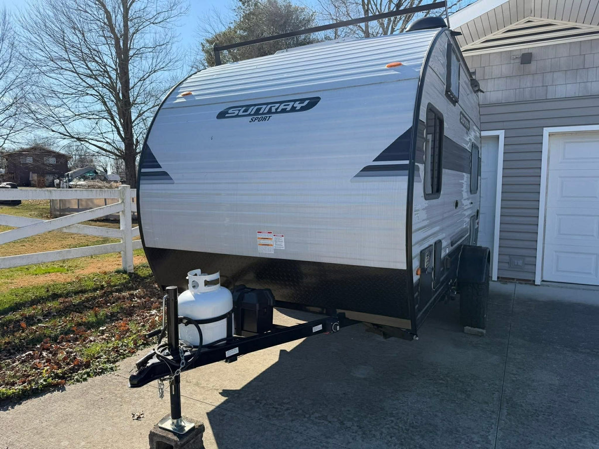 This compact Sunray Sport travel trailer, perfect for an RV rental, sits on a driveway with a propane tank visible upfront. — photo 5