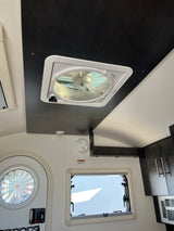 View inside an RV rental with ceiling fan, round window, rectangular window, smoke detector, and kitchen cabinets.