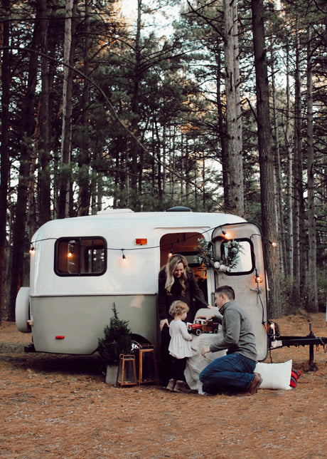 A family enjoys outdoor memories with their charming RV rental, nestled among towering pine trees.