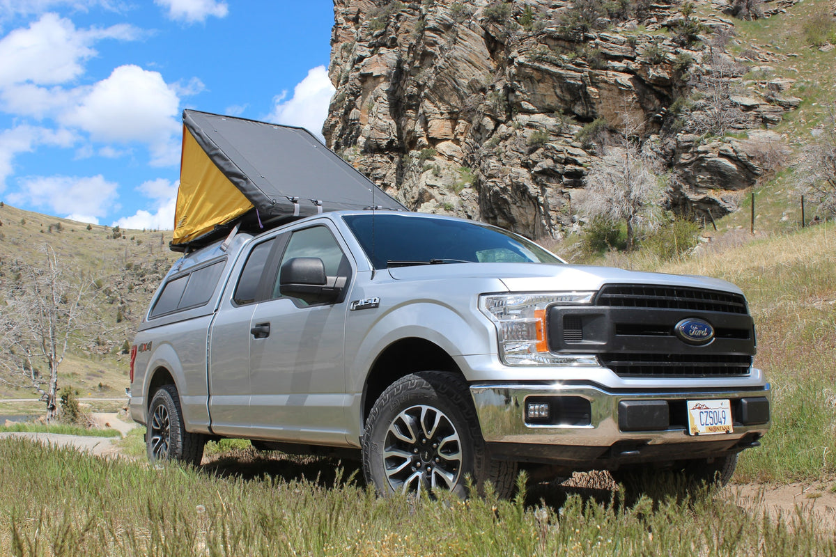 Silver Ford F-150 truck with a rooftop tent, an ideal **rv rental** for mountain camping adventures.