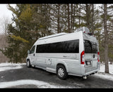 Silver Zion Slumber camper van RV rental parked in a snowy winter forest. Ideal for scenic road trips.