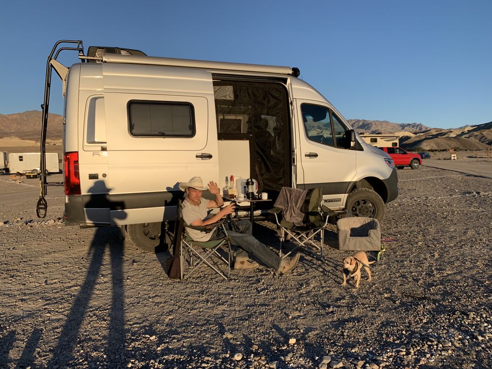 flanked by scenic rear windows overlooking a dry landscape.|RV rental interior: compact wet bath (toilet — photo 1