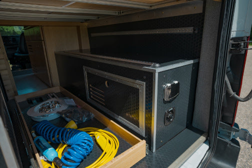 Inside an RV rental: rear storage with a pull-out drawer for gear and a custom power/utility module for convenience.