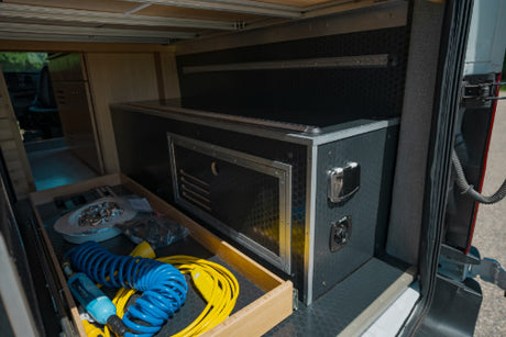 Inside an RV rental: rear storage with a pull-out drawer for gear and a custom power/utility module for convenience.