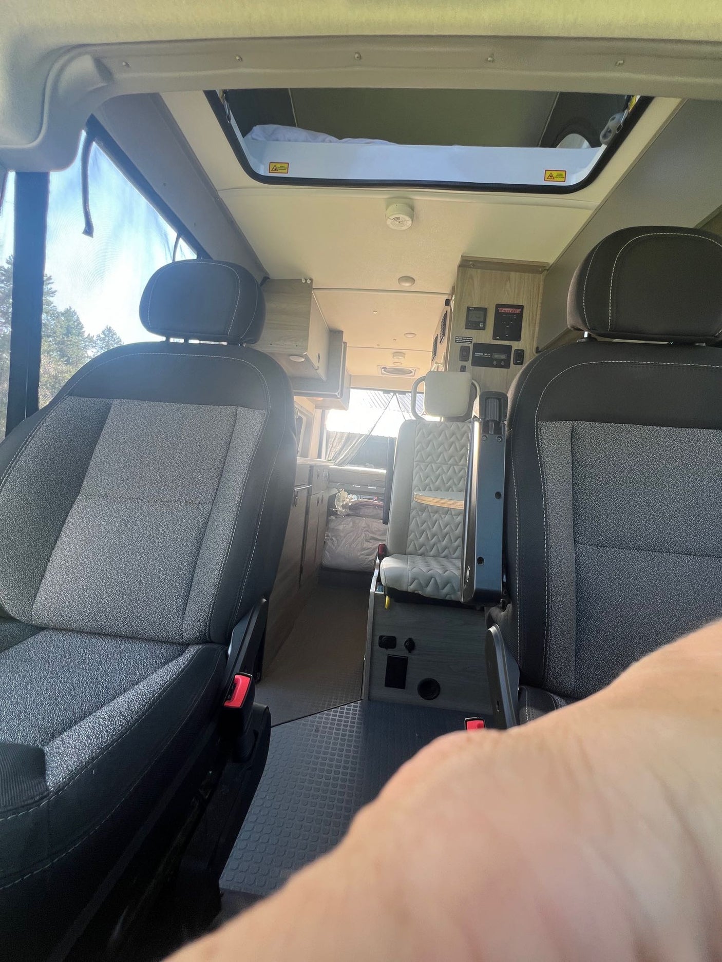 Experience the spacious interior of this RV rental, featuring comfortable front seats and a versatile living area with a pop-top bed.