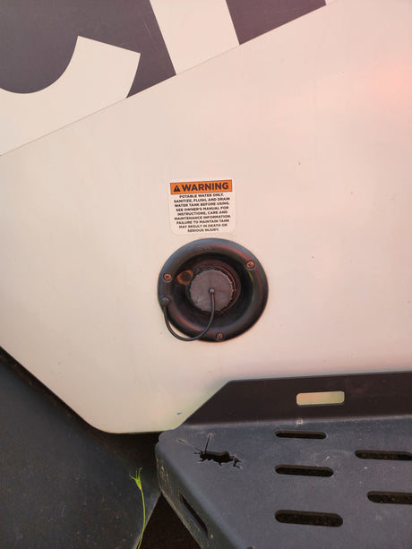An RV rental's fresh water inlet with a warning about potable water and tank maintenance. Essential safety info.
