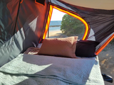 Cozy RV rental camping with a beautiful ocean view from inside the tent, featuring a comfortable bed.