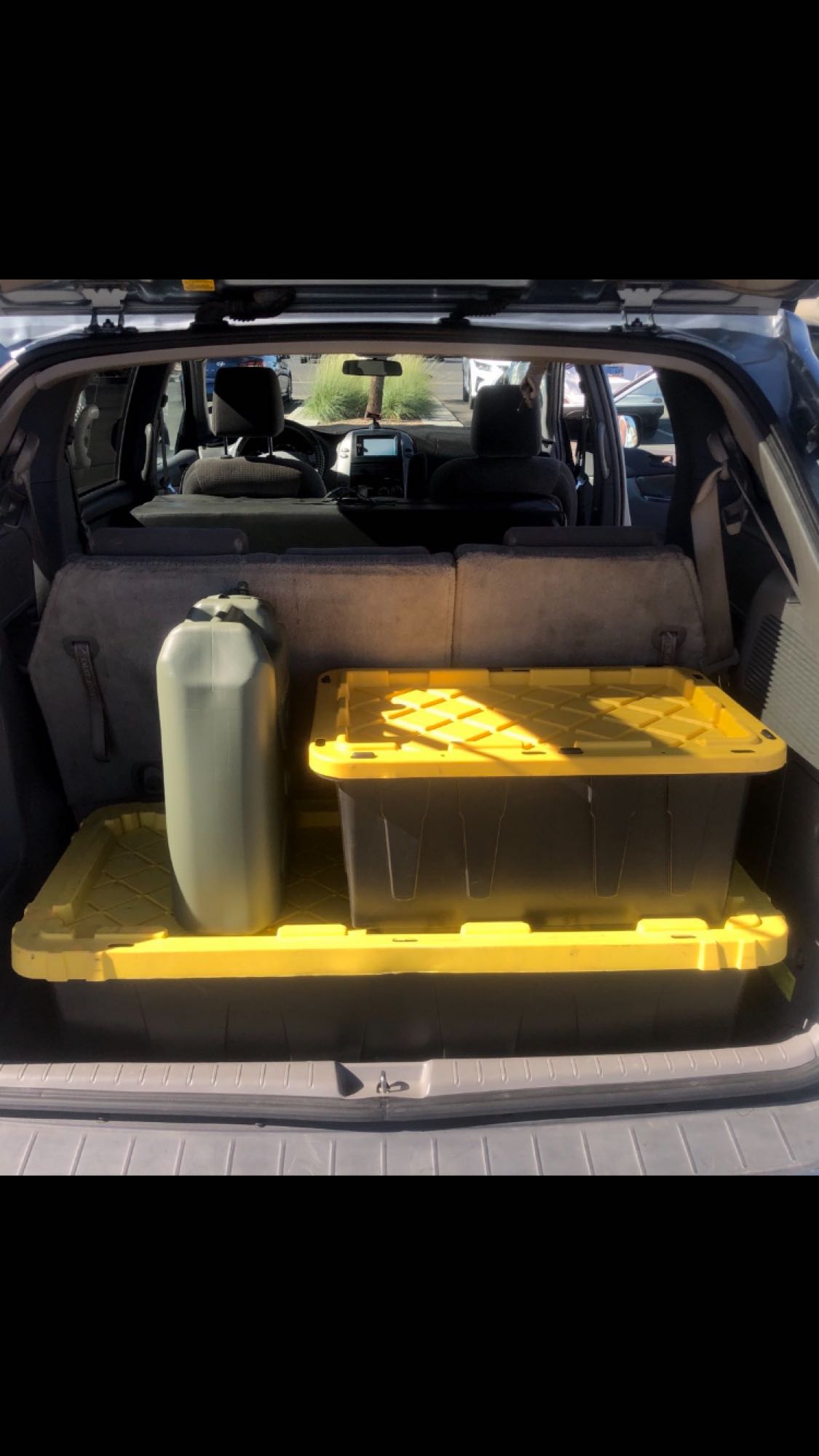  black tote on yellow mat. Gear organized for travel.|Neatly packed vehicle trunk with black and yellow storage totes and a portable heater — photo 14