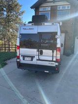Silver Thor Tellaro RV rental with bike rack parked in a sunny driveway outside a house.