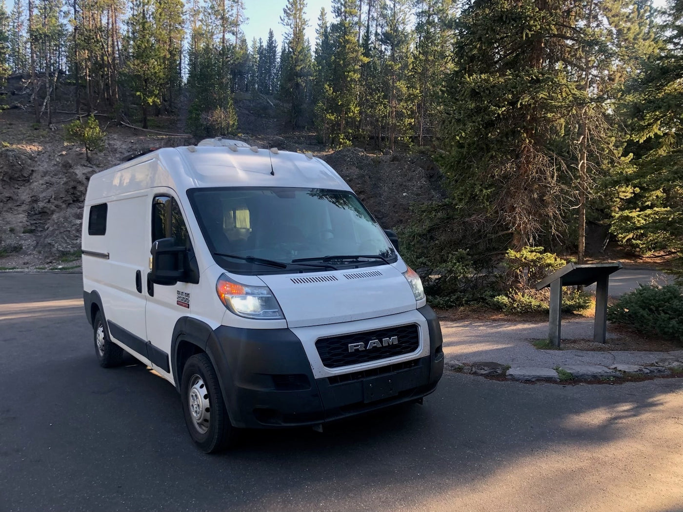  with lush green fields and forested mountains under a clear blue sky. Ideal for nature travel.|White Ram ProMaster camper van — photo 2