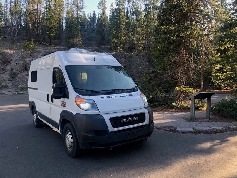  with lush green fields and forested mountains under a clear blue sky. Ideal for nature travel.|White Ram ProMaster camper van — photo 2