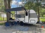 RV rental: This travel trailer features an extended awning, grill, and chairs, creating an inviting outdoor camping setup.