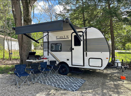RV rental: This travel trailer features an extended awning, grill, and chairs, creating an inviting outdoor camping setup.