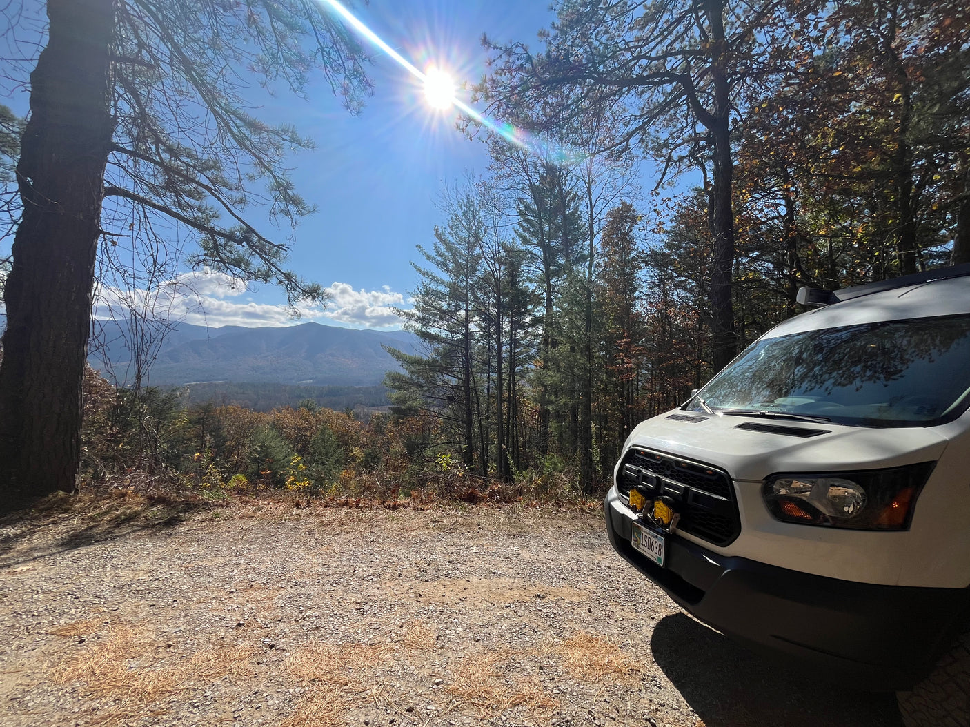 White RV rental van on a gravel road overlooking mountains & valley, perfect for scenic travel & outdoor adventure.