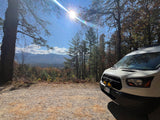 White RV rental van on a gravel road overlooking mountains & valley, perfect for scenic travel & outdoor adventure.