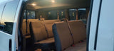 RV rental: Inside a well-lit passenger van showing multiple rows of beige seating and overhead lights.