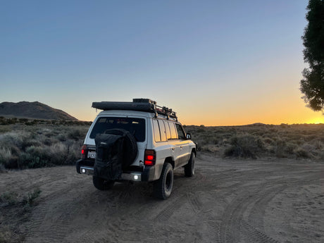 White adventure SUV on a dusty trail at sunset in the desert. Perfect for a rugged rv rental trip.