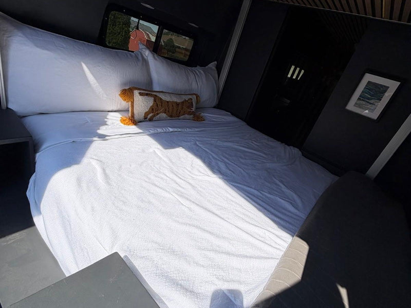  and warm wood-slatted ceiling for a comfortable journey.|Stylish RV rental interior: black kitchen with gold faucet — photo 4