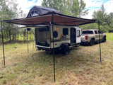 An off-road teardrop trailer with an open galley and rooftop tent, pulled by a pickup, ideal for an rv rental outdoor adventure.