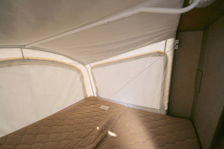 Inside an RV rental pop-up camper: a quilted bed and fabric walls provide a cozy sleeping area.