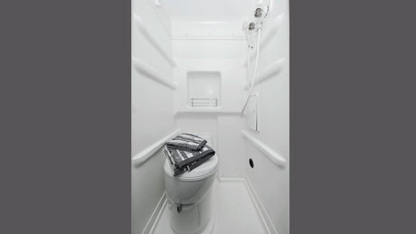 Inside an RV rental: compact white bathroom with toilet, shower & shelf.