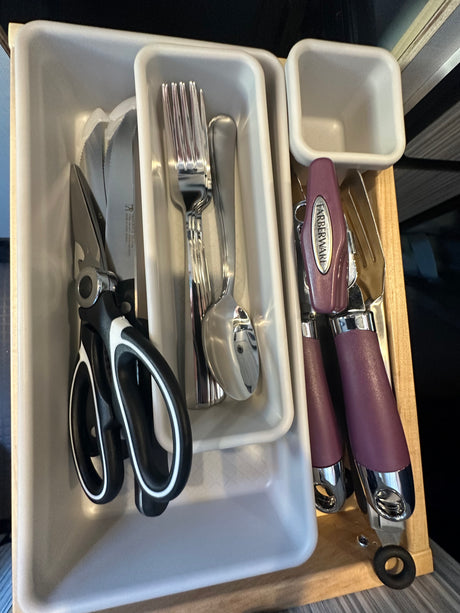 RV rental kitchen drawer organizer with kitchen shears, knives, and Farberware cutlery, neatly stored for small spaces.