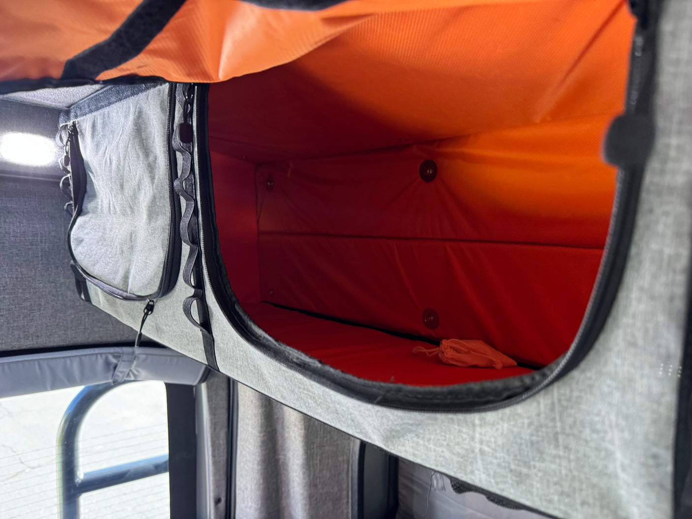 RV rental interior: An open gray fabric storage compartment with a bright orange lining, ready for your travel essentials.