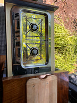 An RV rental's Dometic 2-burner stove with a wooden cutting board, ideal for cooking meals on the go in a camper.