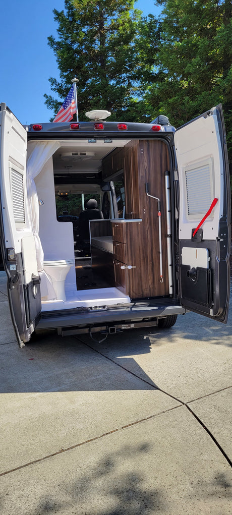 Explore this RV rental's interior: compact bathroom, kitchen, and an American flag proudly displayed on top. Perfect for travel.