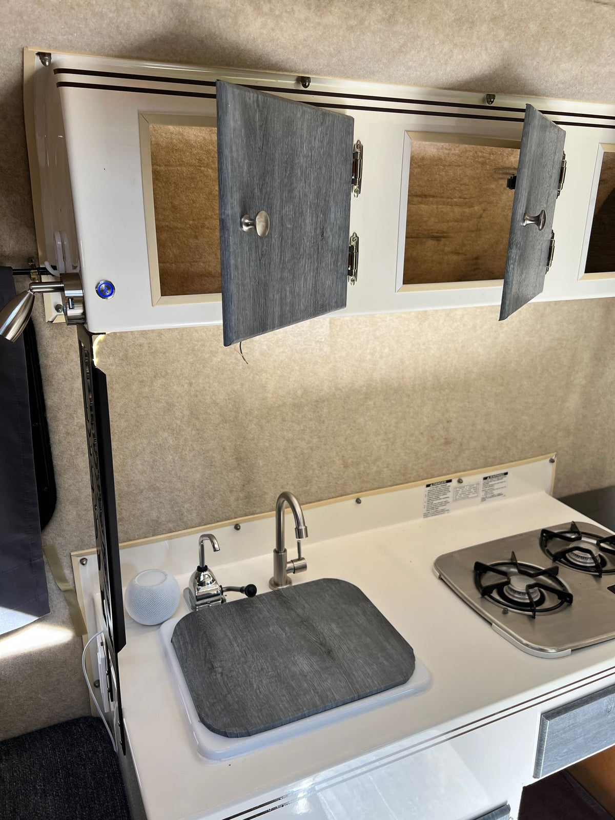 RV rental kitchen: compact sink, stove, and open overhead cabinets showing smart storage in a modern interior. — photo 13