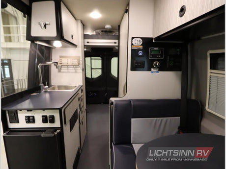 This RV rental interior features a compact kitchenette with a sink, a user-friendly control panel, and comfortable seating with a table.