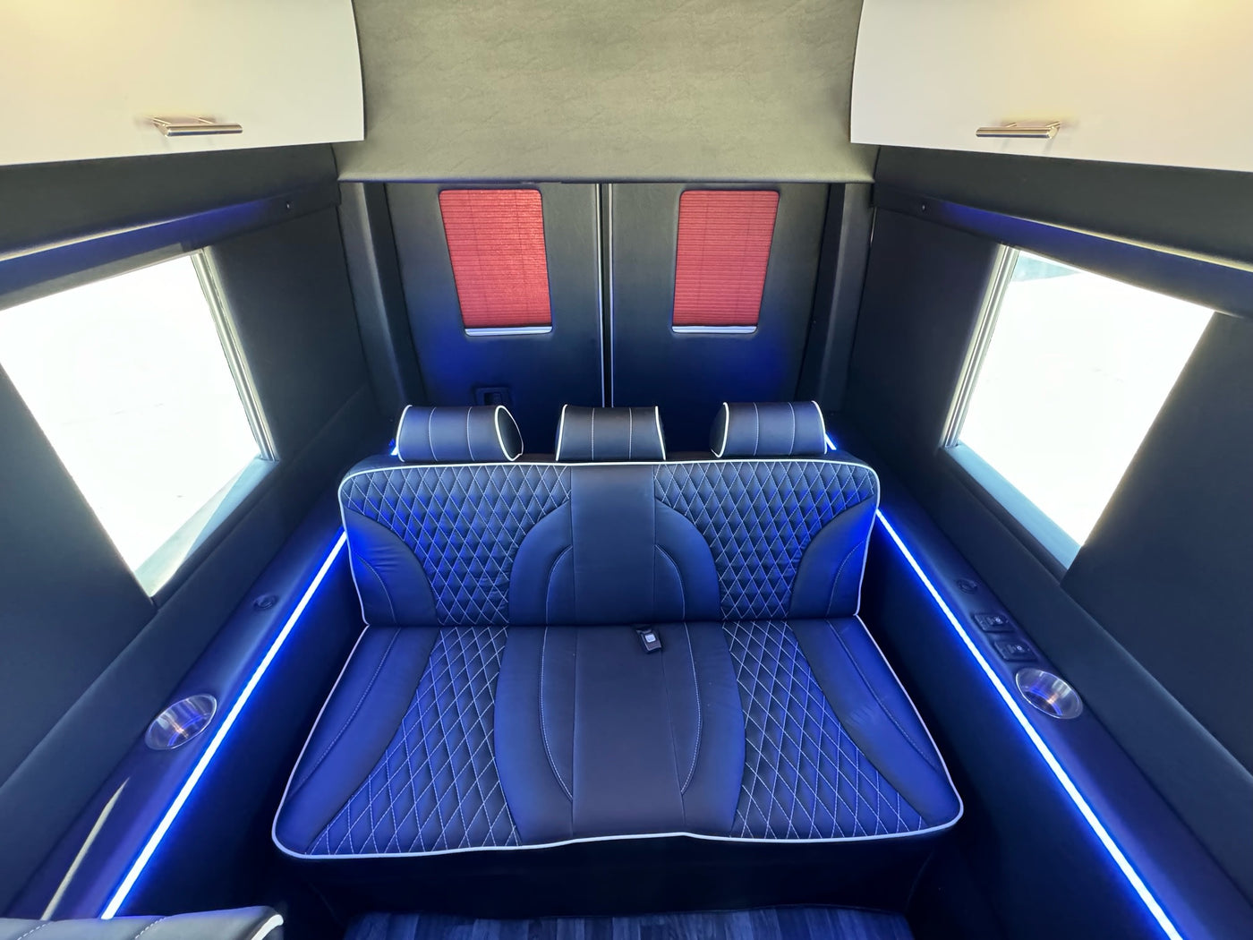  and blue accent lighting.|Plush black leather interior of a high-end RV rental van — photo 4