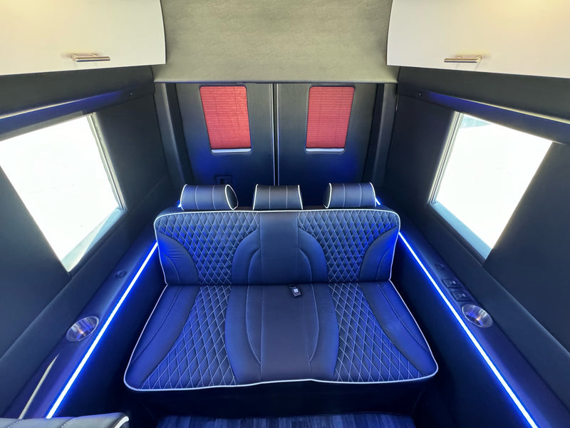  and blue accent lighting.|Plush black leather interior of a high-end RV rental van — photo 4