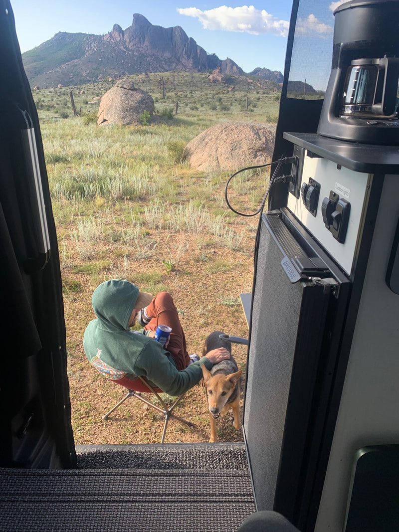  perfect for remote adventures.|RV rental bedroom with a comfy bed and a stunning view of golden fields and mountains from the large window.|Cozy RV rental interior: a bed and dog bed overlook a stunning mountain vista through the rear window. Perfect for adventure.|From an RV rental — photo 5