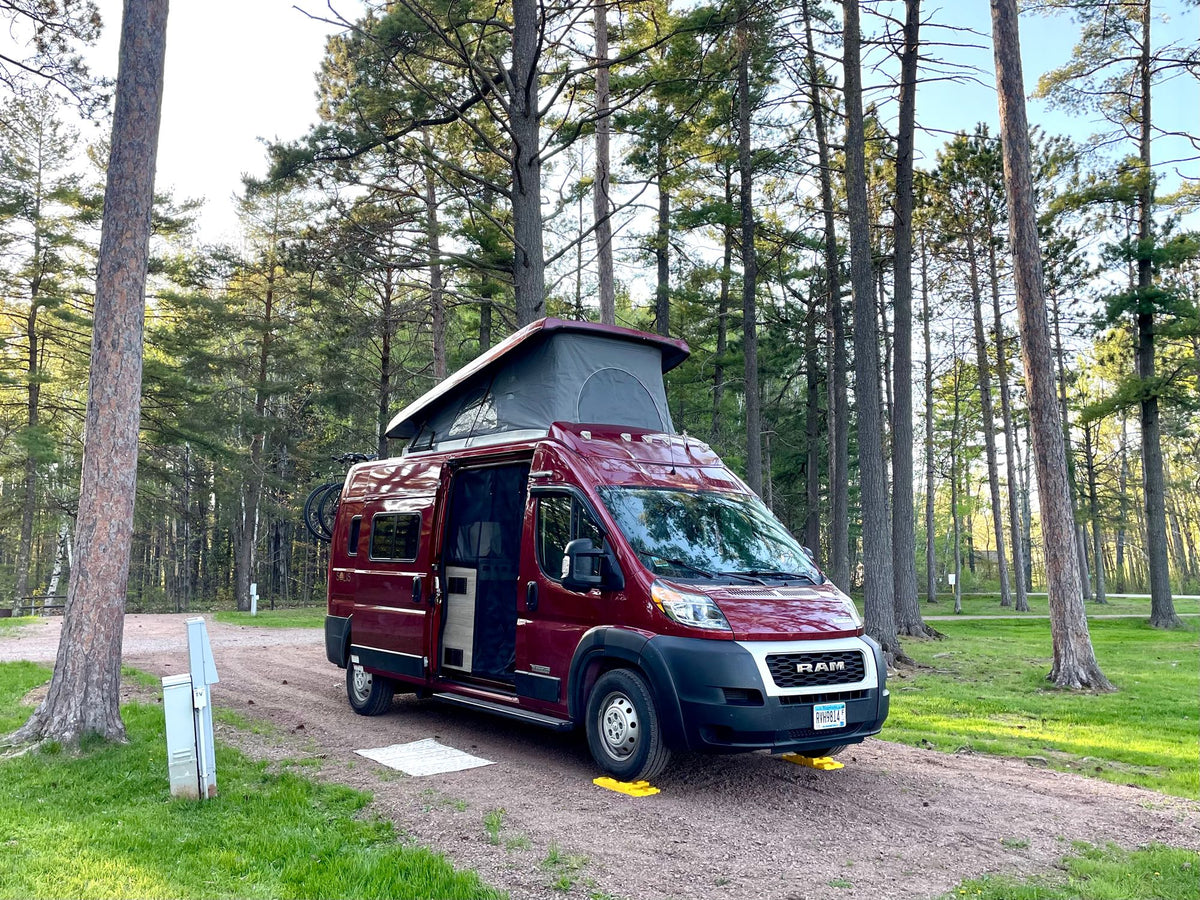 This red **RV rental** is perfectly leveled at a tranquil pine forest campsite