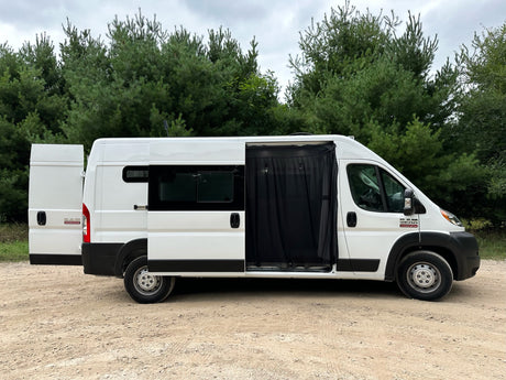 White camper van parked on dirt road, rear and side doors open with mesh screen. Ideal for RV rental trips.