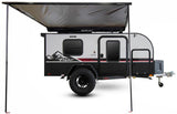 Explore the wild with this rugged black & grey Flyer Pursue off-road travel trailer, shown with an extended awning, ready for RV rental.