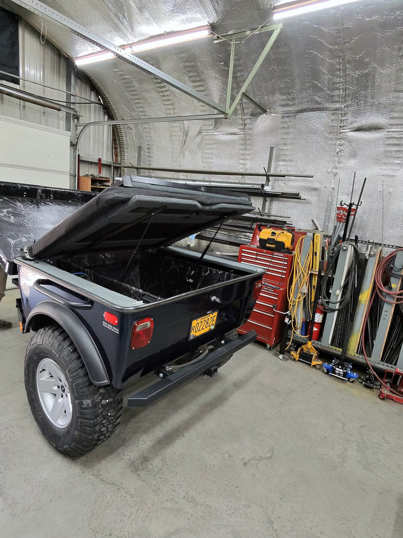 Rugged utility trailer with open bed and off-road tires, perfect for your next rv rental camping trip, inside a workshop. — photo 6