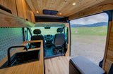 Spacious RV rental interior with a modern kitchen, wood paneling, and an inviting view of green fields and mountains.