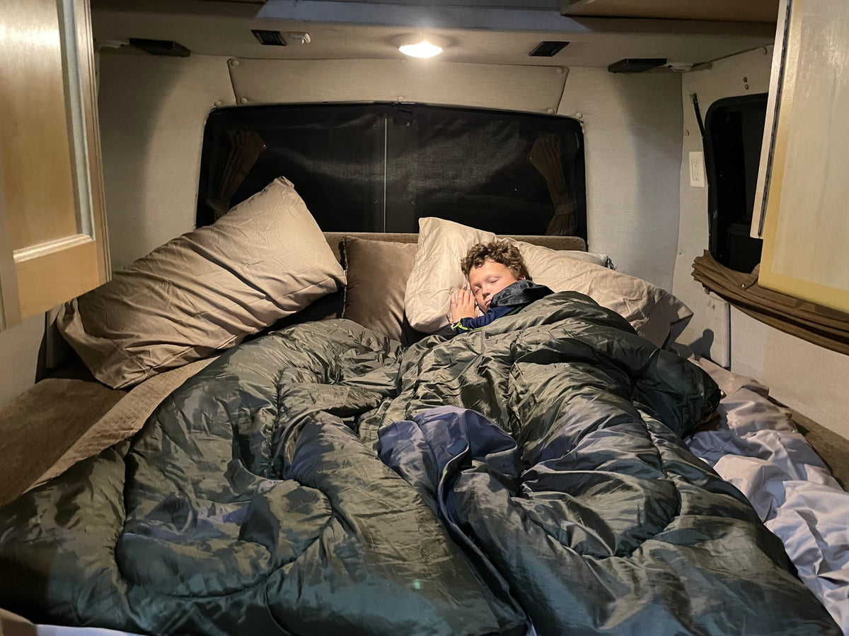 under a cloudy sky.|Cozy RV rental interior featuring a U-shaped dinette with cushions & central table — photo 3