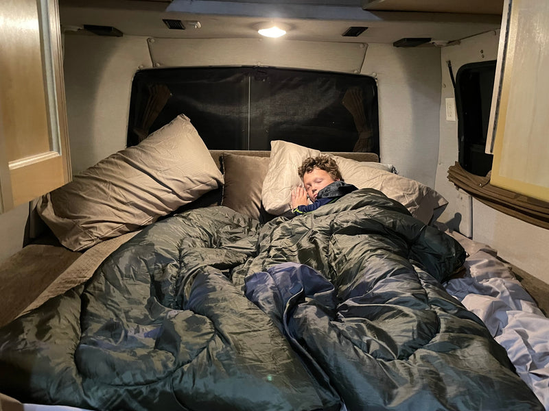  under a cloudy sky.|Cozy RV rental interior featuring a U-shaped dinette with cushions & central table — photo 3